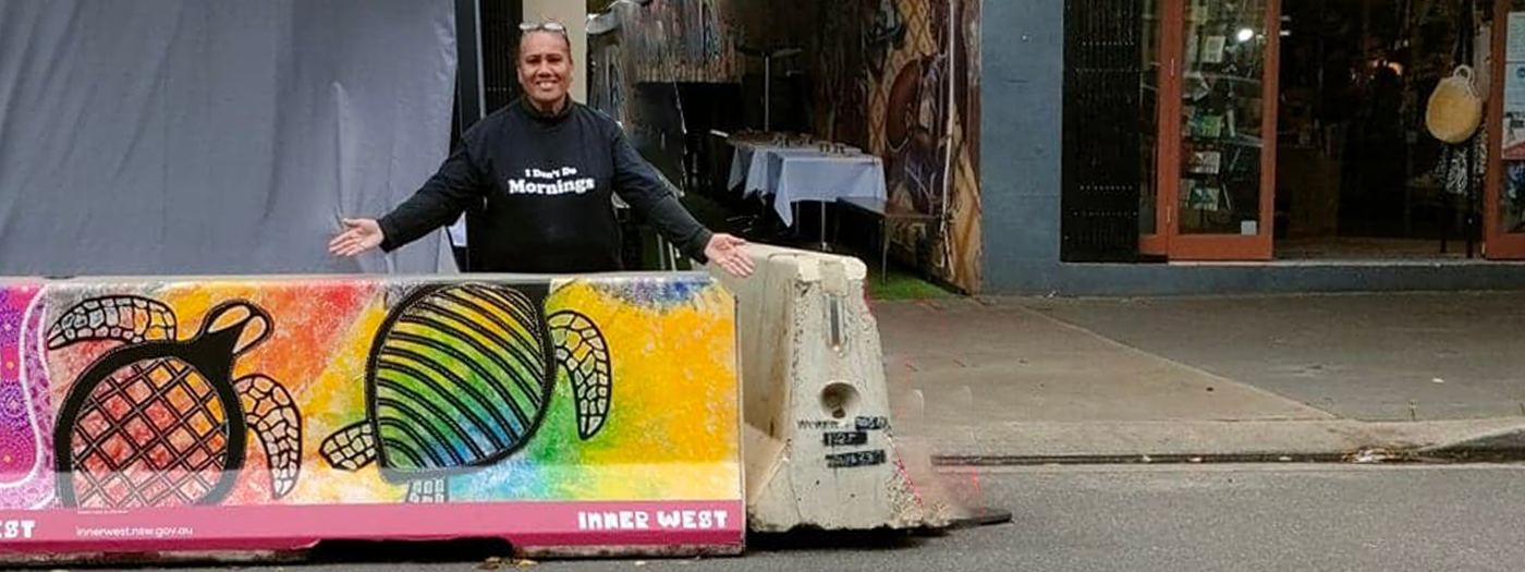 Artist standing behind her artwork featured on Inner West roadside buffer