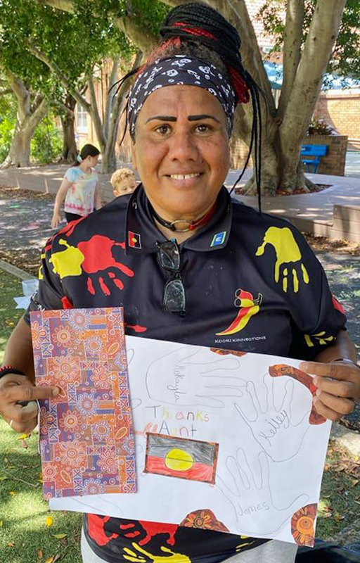 Jude Jarrett smiling, holding appreciation card from community work